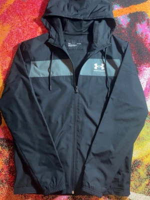 Under Armour Windbreaker - Vindjacka - Säljer en svart under armour vindjacka, Storlek S, har använts 3-4 gånger bara, nyskick !PRIS KAN DISKUTERAS!