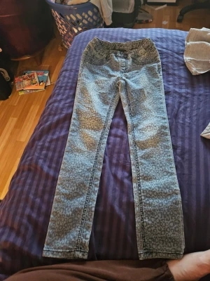Leopardmönstrade skinny jeans - Säljer ett par ljusblå jeans med leopardmönster och smal passform. Byxorna har resår i midjan och klassiska bakfickor. Materialet är jeans och de har en riktigt cool look som sticker ut.
