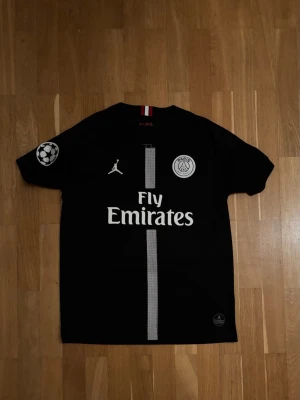 Neymar 2018/2019 Tredje Tröja - Svart Paris Saint-Germain tröja med Neymar Jr #10 på ryggen. Jordan-edition med Fly Emirates-tryck framtill samt Champions League-patch på ärmen. Passar lika bra till match som till streetwear
