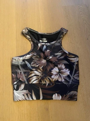 Blommig träningstop xs stronger - En brun blommig träningstop från stronger, i storlek xs. Ett skönt material med tjocka band 