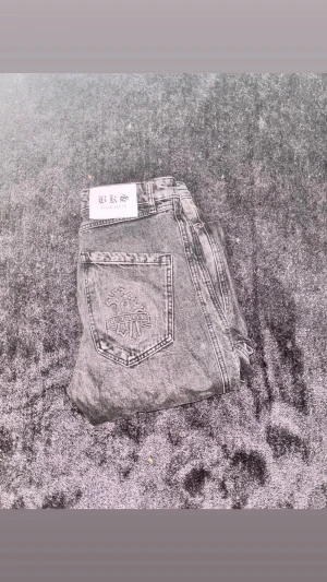 Svarta Y2K jeans med broderad bakficka - Säljer ett par svarta jeans från BKS Black Squad med broderad detalj på bakfickan. Jeansen har en rak passform och klassisk femficksdesign. Materialet är denim och färgen är tvättad svart med slitna detaljer för en cool Y2Klook.