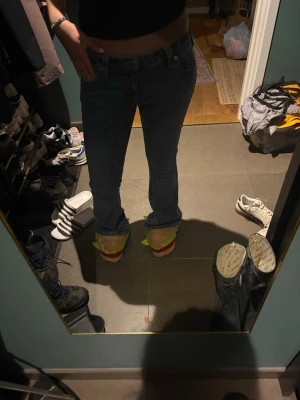 Blå bootcut jeans från True Religion - Säljer ett par klassiska blå jeans från True Religion med bootcut passform och låg midja. Jeansen har snygga kontrastsömmar, ikoniska bakfickor och silverfärgade detaljer. Perfekta för dig som gillar en tidlös och avslappnad look.