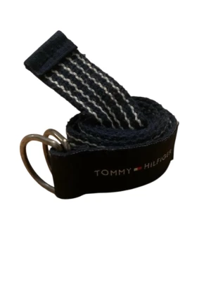 Randig marinblå bälte från Tommy Hilfiger - Säljer en marinblå och vit randig bälte från Tommy Hilfiger. Bältet har dubbla metallringar för stängning. Perfekt accessoar för att lyfta din outfit med en snygg touch 