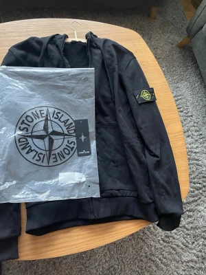Stone island zip  - Säljer en äkta Stone Island zip hoodie i mycket fint skick. Använd fåtal gånger och väl omhändertagen. Klassisk design med den ikoniska Stone Island-loggan på ärmen. Dragkedja framtill och bekväm passform – perfekt både till vardag och finare outfits.