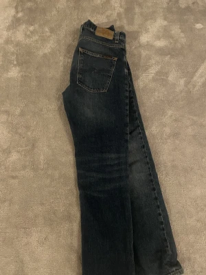 Mörkblå jeans från Nudie Jeans - Säljer ett par mörkblå jeans från Nudie, modellen är grim Tim och är insydda i midjan, till en 29 i midjan  och längden är 30 