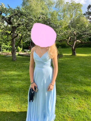 Ljusblå långklänning med smala band - Säljer en elegant ljusblå långklänning med smala axelband och omlottdetalj vid bysten. Klänningen har v-ringning och ett flytande, svepande fall som ger en riktigt drömmig känsla. Perfekt till student eller bal! Materialet känns lätt och svalt. Köpte från plick för 2500 men säljer för 1500 men pris kan diskuteras! Då den är använd två gånger.