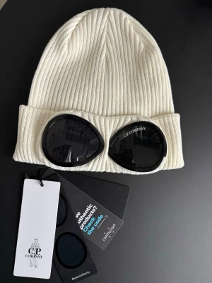 C.P. Company white beanie, brand new - Säljer den ikoniska vita ribbstickade mössan från C.P. Company. Aldrig använd, prislappen och andra etiketter kvar! // Selling the iconic white ribbed knit hat from C.P. Company. Never worn, price tag and other labels still on!