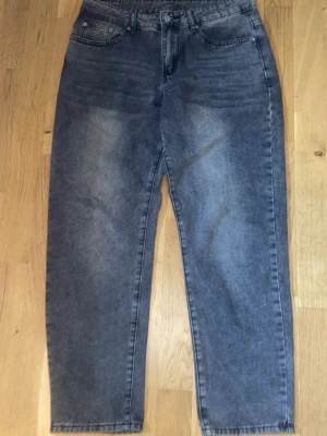 Mörkblå raka jeans med hög midja - Säljer ett par mörkblå jeans med rak passform och hög midja. Klassisk femficksmodell med knapp och dragkedja framtill. Jeansen har en tvättad look och är tillverkade i kraftigt denimtyg. Perfekta till sneakers eller boots.