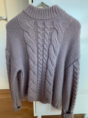 stickad tröja Sofie Schnoor - Mysig stickad tröja från Sofie Schnoor med grova flätstickade detaljer fram och längs ärmarna. Tröjan har en hög ribbad krage och långärmade muddar. Perfekt för kyliga dagar och enkel att styla. Storlek 152 men väldigt oversized och passar mig som brukar ha xs-s annars💗