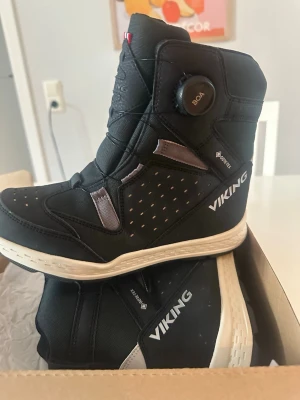 Svarta Viking  - Säljer ett par svarta Viking Espo Reflex Warm GTX boots med BOA-snörning. Skorna är vattentäta med Gore-Tex och har vit sula samt reflexdetaljer. Perfekta för kalla dagar och enkel att ta på tack vare BOA-systemet.