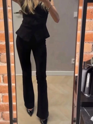 Svarta bootcut kostymbyxor från Zara - Säljer ett par svarta kostymbyxor från Zara med bootcut passform. Byxorna har hög midja och är tillverkade i ett mjukt, välsittande material som ger en clean och stilren look. Perfekta till en snygg topp eller kavaj för en trendig outfit.