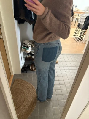 Ljusblå jeans med mörk bakficka från H&M -   jeans med mörkblå patchad bakficka och raka ben. Jeansen har flätade detaljer vid fickorna fram. Storlek 36. 