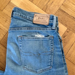 Blå jeans från Polo Ralph Lauren - Snygga blå jeans från Polo Ralph Lauren med klassisk femficksdesign och läderpatch bak i midjan. Jeansen har en ljus tvätt och subtil slitning ovanför bakfickan för en cool, avslappnad look. Perfekta till sneakers eller boots.