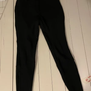 Svarta fodrade ridbyxor  - Svarta ridbyxor med helskodd silikonprint för extra grepp i sadeln. Tight passform och stretchigt material som ger bra rörelsefrihet. Klassisk look med bälteshällor och smala ben. Dom är fodrade ( med flis) inuti så perfekt nu till vintern dom tål även regn ( skriv för fler bilder)   Nypris 900kr