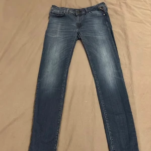 Replay Hyperflex  jeans i mörkblå denim - Snygga skinny jeans från Replay i mörkblå tvätt med diskreta slitningar. Klassisk femficksmodell med Replay-logga på fickan och läderpatch bak i midjan. Jeansen har smal passform och är tillverkade i stretchig denim för extra komfort.