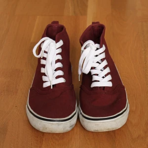 Vinröda sneakers - Snygga vinröda sneakers med klassisk vit sula och vita snören. Skorna har en rund tå och är tillverkade i textilmaterial. Perfekt färg för hösten. Är använda men i ett bra skick.