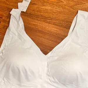 Vit bralette topp från Cubus 3XL - Säljer en vit bralette topp från Cubus i storlek 3XL. Toppen har v-ringning och är ärmlös med breda axelband. Tillverkad i mjuk och stretchig syntetblandning för en bekväm passform. Perfekt för en clean och enkel look.