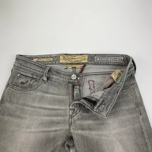 Grå limited edition jeans Jacob Cohen - Snygga grå jeans från Jacob Cohen, limited edition 15 av 25. Klassisk femficksmodell med silverfärgad logotyp på bakfickan och unika detaljer som broderad etikett och kontrastsömmar. Jeansen har en rak passform och är tillverkade i mjukt bomullsjeansmaterial.