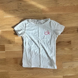 Vit t-shirt från Calvin Klein - Vit t-shirt från Calvin Klein med röd 'ck'-logga broderad på bröstet. Barnstorlek men passar mig som har S