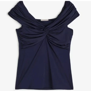 Mörkblå omlott topp med twist - Säljer min  mörkblå offshoulder topp  med en  twistdetalj framtill då jag inte använder den längre. Den är i bra skick och använd väl