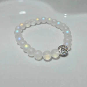 Vitt pärlarmband med glittrande kula - Superfint armband med runda, halvgenomskinliga vita pärlor och en glittrig silverfärgad kula som detalj. Pärlorna har en lätt regnbågsskimrande effekt som gör armbandet extra unikt och snyggt. Perfekt för dig som gillar stilrena smycken med lite extra bling.