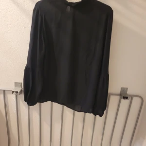 Svart blus från Stockh LM - Säljer en svart blus från Stockh LM i storlek 40. Blusen har långa ärmar med lätt puff och är tillverkad i ett tunt, flowy material som ger en snygg siluett. Perfekt för dig som gillar stilrena och klassiska plagg.