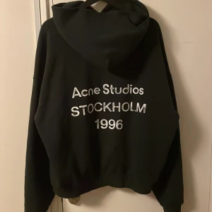Acne Studios hoodie  - Svart oversized hoodie från Acne Studios med stor huva och tryck i silvertext på ryggen: 'Acne Studios Stockholm 1996'. Mjuk bomullskvalitet i väldigt bra skick. Storlek S passar dig som är 175-185 beroende på hur man vill att passformen ska vara.