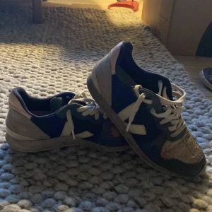 Veja sneakers i blått och beige - Säljer ett par super fina Veja sneakers med blå textil, beige och grå detaljer samt vita snören. Skorna har en unik struktur på tån och klassisk Veja-logga på sidan och hälen. Snygg design med platt sula och rund tå. Perfekta för dig som gillar stilrena och trendiga sneakers. Storlek 39, hör av dig om du har frågor eller funderingar!