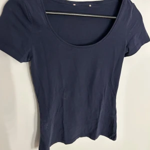 Mörkblå enkel kortärmad topp - En basic mörkblå topp med rund halsringning och korta ärmar. Modellen är figurnära.