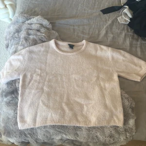 Ljusrosa stickad tröja från Lindex -  ljusrosa stickad tröja från Lindex med korta ärmar och rund halsringning. Är mer rosa i verkligheten, ser mer beig ut på kameran 