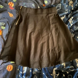 Simpel svart kjol - Väldigt simpel svart kjol. Typ till mitten av låren i längd. Dragkedja är väldigt stabil. Men väldigt smal i midlan. Den sitter lätt ovanför navel eller glider upp. Har aldrig på mig kjol så aa