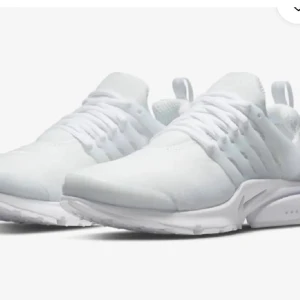 Nike Presto helvita sneakers - Säljer ett par helvita Nike Presto sneakers med mesh-ovandel, syntetiska detaljer och snörning. Skorna har rund tå, platt sula och diskret Nike-logga på sidan och tungan. Perfekta för dig som gillar stilrena och sportiga sneakers.