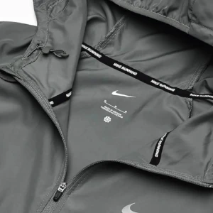 Grå vindjacka nike Miller - Snygg grå vindjacka från Nike Running med huva och dragkedja framtill. Jackan har minimalistisk design med Nike-logga på bröstet och justerbar dragsko i huvan. Perfekt för löprundan eller när du vill ha en sportig look.