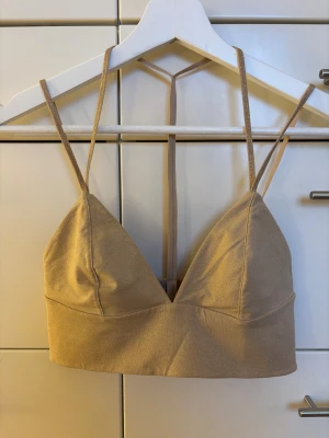 Guldtopp med smala band, storlek 36 - Grymt snygg guldtopp med v-ringad front och smala band från HM Studio i storlek 36. Perfekt till jul- och nyårets fester!