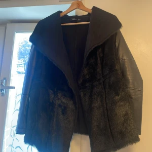 Svart pälsjacka med skinnärmar - Snygg svart pälsjacka från esmara med stora slag och coola skinnärmar. Jackan har en oversized passform och är tillverkad i fuskpäls och syntetiskt skinn. Perfekt för dig som vill sticka ut med en statementjacka i vinter.