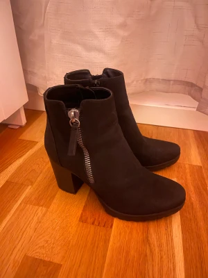 Svarta stövletter med klack och dragkedja - Snygga svarta stövletter i mockaimitation med grov klack och markerad dragkedja på sidan. Använda fåtal gånger. Jätte fint skick. Perfekta för dig som vill ha en stilren men cool look till höst, vår och vinter. 