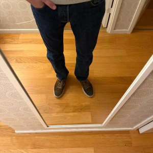 Levi's 501 mörkblå jeans W30 L32 - Säljer ett par klassiska Levi's 501 jeans i mörkblå tvätt. Modellen har rak passform och normal midja, med fem fickor och gul kontrastsöm. Jeansen är tillverkade i slitstarkt bomullsdenim och har den ikoniska läderpatchen bak.