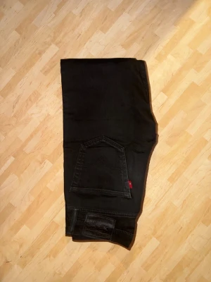 Levi's 512 svarta skinny jeans - Svarta Levi's 512 jeans med skinny fit och klassisk femficksdesign. Jeansen har en smal siluett, silverfärgade nitar och knapp, samt den röda Levi's-taggen på bakfickan. Materialet är stretchigt jeans för extra komfort och passform.