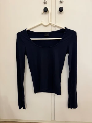 Mörkblå långärmad topp Gina Tricot - Säljer en mörkblå långärmad topp från Gina Tricot i storlek XXS. Toppen har en djup rundad urringning och är figurnära i modellen. Säljer för att den aldrig kommer till användning och är max använd en gång!💕