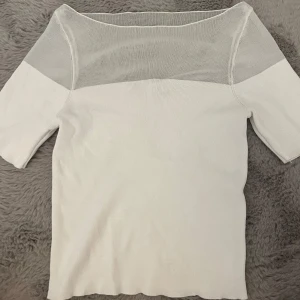 Vit topp med mesh från Zara Stockholmsstil - Vit topp från Zara med korta ärmar och snygg meshdetalj upptill över axlar och halsringning. Toppens har en enkel, stilren look som passar perfekt till jeans eller kjol. Materialet känns mjukt och lätt.