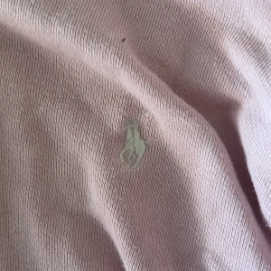 Ljusrosa hoodie från Polo Ralph Lauren - Säljer en ljusrosa hoodie från Polo Ralph Lauren med dragkedja och klassisk broderad logga på bröstet. Tröjan har huva, långa ärmar och är tillverkad i mjuk bomull. Perfekt för en chill och avslappnad stil. Ordinarie priset är 1200kr