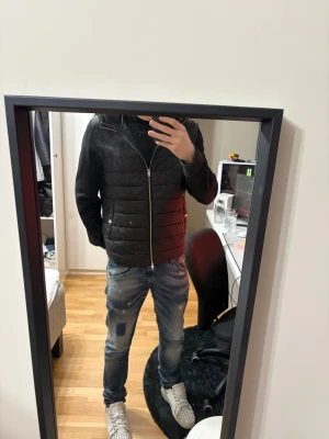 Svart cardigan med huva - Säljer en svart cardigan från HM med huva och dragkedja framtill. Jackan har quiltade paneler och en clean, modern look som passar perfekt till jeans. Jag är 181 72kg, mycket bra skick! BVSA
