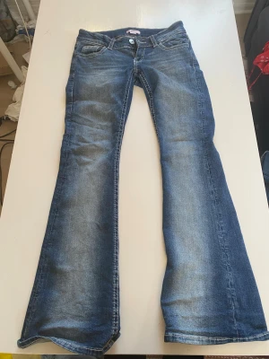 Blå bootcut jeans från Gina Tricot - Snygga blå bootcut jeans från Gina Tricot med broderade bakfickor och dekorativa knappar. Dem är använd kanske upp till 10 ggr💕kan diskutera priset