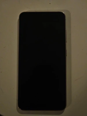 Samsung Galaxy S23 - Samsung Galaxy S23 i ljuslila färg med trippelkamera. Telefonen har en spricka på baksidan men ser annars ut att vara i gott skick. Perfekt för dig som vill ha en kraftfull Android-telefon med snygg design och bra kamera.