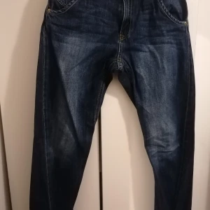 Mörkblå jeansbyxor från Lindex, strl 152 - Snygga mörkblå jeansbyxor från Lindex i storlek 152. Modellen heter Detroit och har elastiska muddar vid bensluten för en cool och avslappnad look. Klassisk femficksdesign och kontrastsömmar. Perfekta för dig som gillar streetstyle och bekväma jeans.