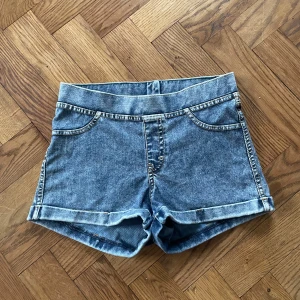 Blå denimshorts från H&M, strl 158 - Snygga blå denimshorts från H&M i klassisk femficksmodell med uppvikta benslut. Shortsen har normal passform och är tillverkade av bomull, polyester och elastan för en skön stretch. Perfekta för varma dagar och enkel att matcha med din favorit-topp.