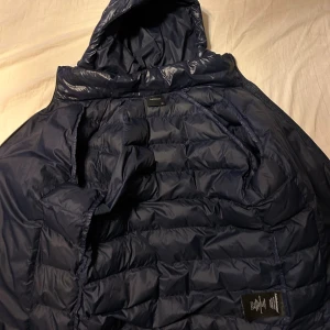 Sällsynt Mörkblå Peak Performance dunjacka - Säljer en mörkblå dunjacka från Peak Performance. Jackan har quiltad design och logotyp på ärmen. Perfekt för kalla dagar och har en snygg, sportig look. Priset är inte hugget i sten vill bli av med jackan så är du intresserad skriv till mig så löser vi ett bra pris