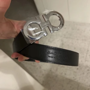 Svart bälte från Salvatore Ferragamo - Stilrent och unikt bälte från Ferragamo, för dig som vill sticka ut och vara unik. Pris kan diskuteras vid snabb affär. Bältet är oanvänt och kommer med plast på. Perfekt julklapp!