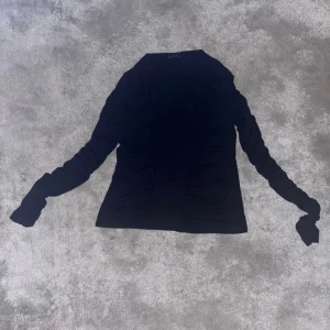 Svart långärmad topp från Gina Tricot - Svart långärmad topp från Gina Tricot i storlek XL men kan även passa storlek L. Toppen har rynkade detaljer längs sidorna och är tillverkad i ett mjukt, stretchigt material som sitter skönt. Knappt använd, väldigt bra skick. Säljer för att jag inte använder tröjan! 💕💕