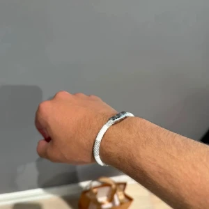 Vitt armband med silverlås - Snyggt vitt armband med ett stilrent silverfärgat lås. Armbandet har en diskret meshstruktur som ger det en modern känsla. Perfekt för dig som gillar minimalistiska accessoarer med en touch av elegans.